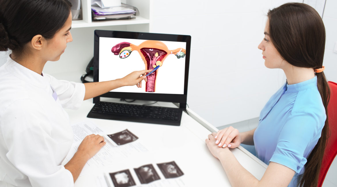 A doctor uses an image on a laptop to educate a patient on her uterine fibroids.